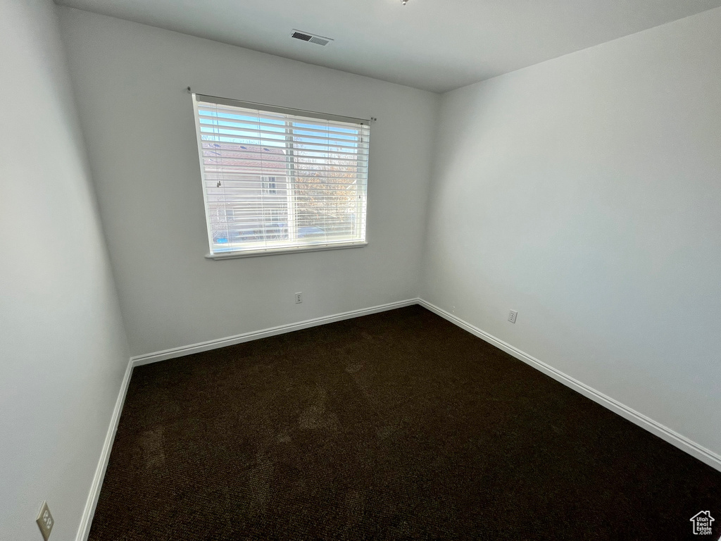 Empty room featuring dark carpet and baseboards