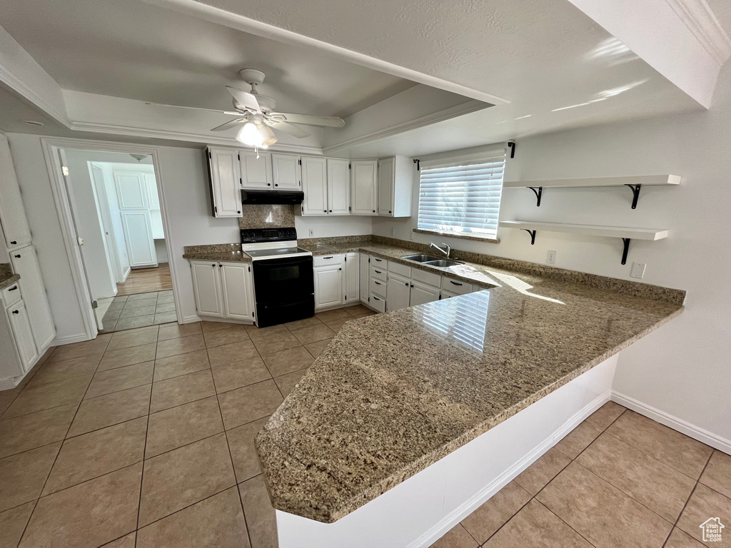 Kitchen featuring range with electric stovetop, a sink, under cabinet range hood, light tile patterned floors, and open shelves