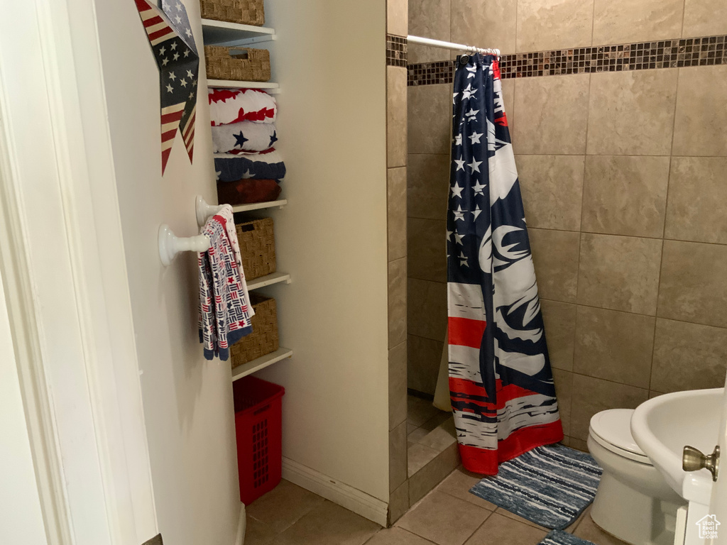 Bathroom with tiled shower, tile patterned floors, and toilet
