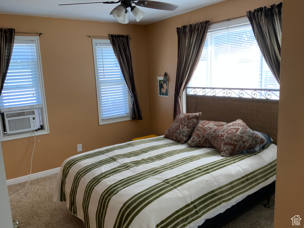 Carpeted bedroom featuring cooling unit, baseboards, and a ceiling fan