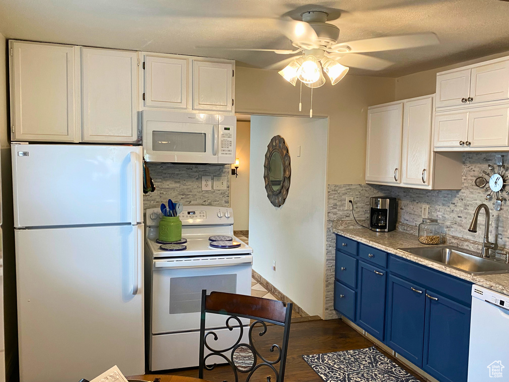 Kitchen featuring white appliances, blue cabinetry, a sink, ceiling fan, and white cabinetry