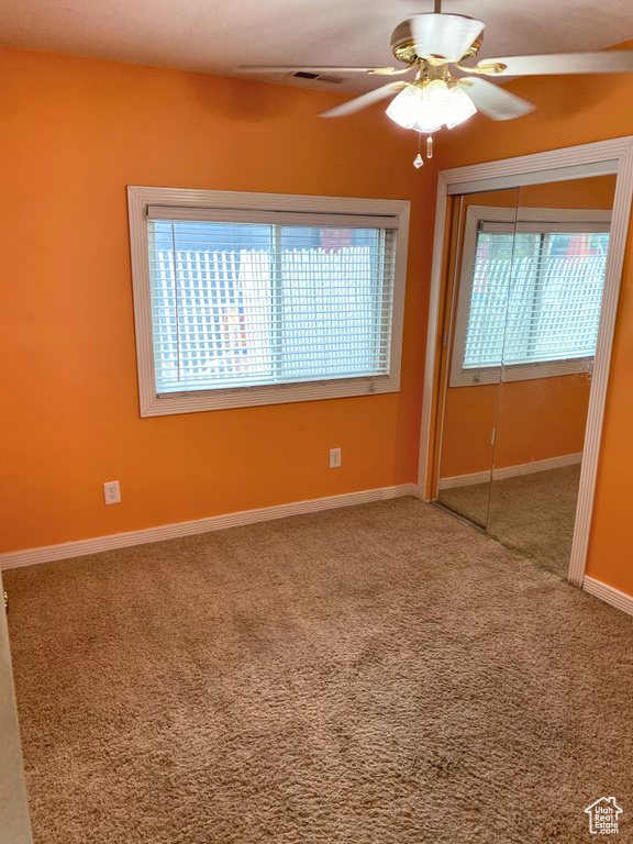 Spare room featuring healthy amount of natural light, carpet, ceiling fan, and baseboards