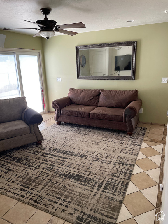 Living area featuring light tile patterned floors and a ceiling fan