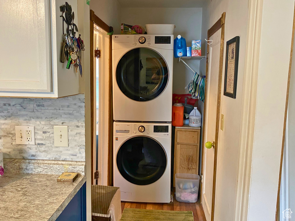 Laundry area with estacked washer and dryer and wood finished floors