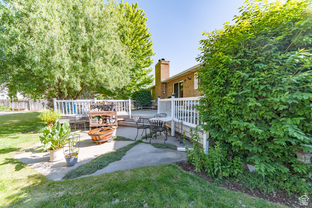 View of green lawn with a patio and a wooden deck