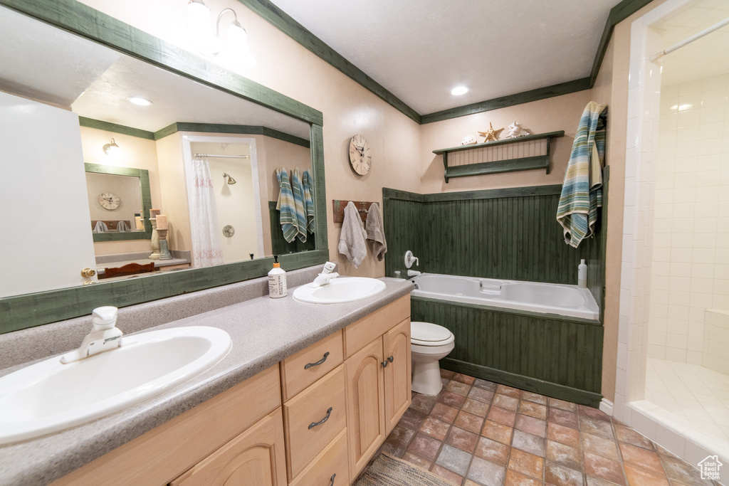 Bathroom featuring a bath, tiled shower, double vanity, toilet, and stone finish floors