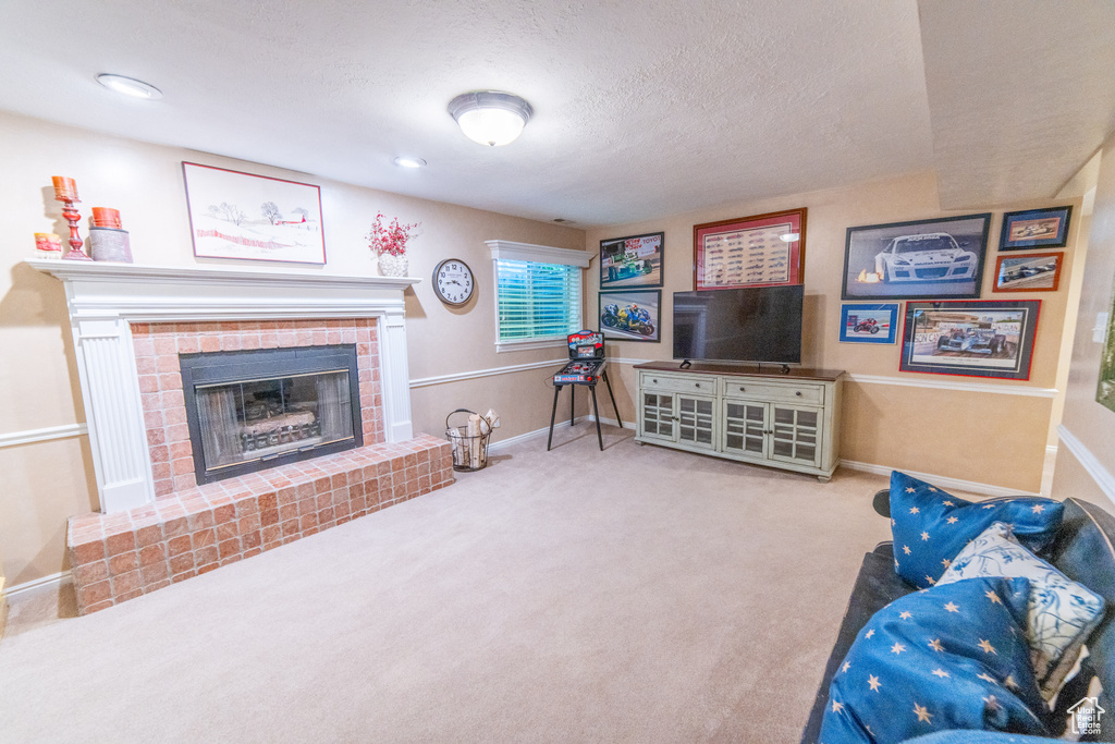 Living room with a fireplace, baseboards, carpet, and a textured ceiling