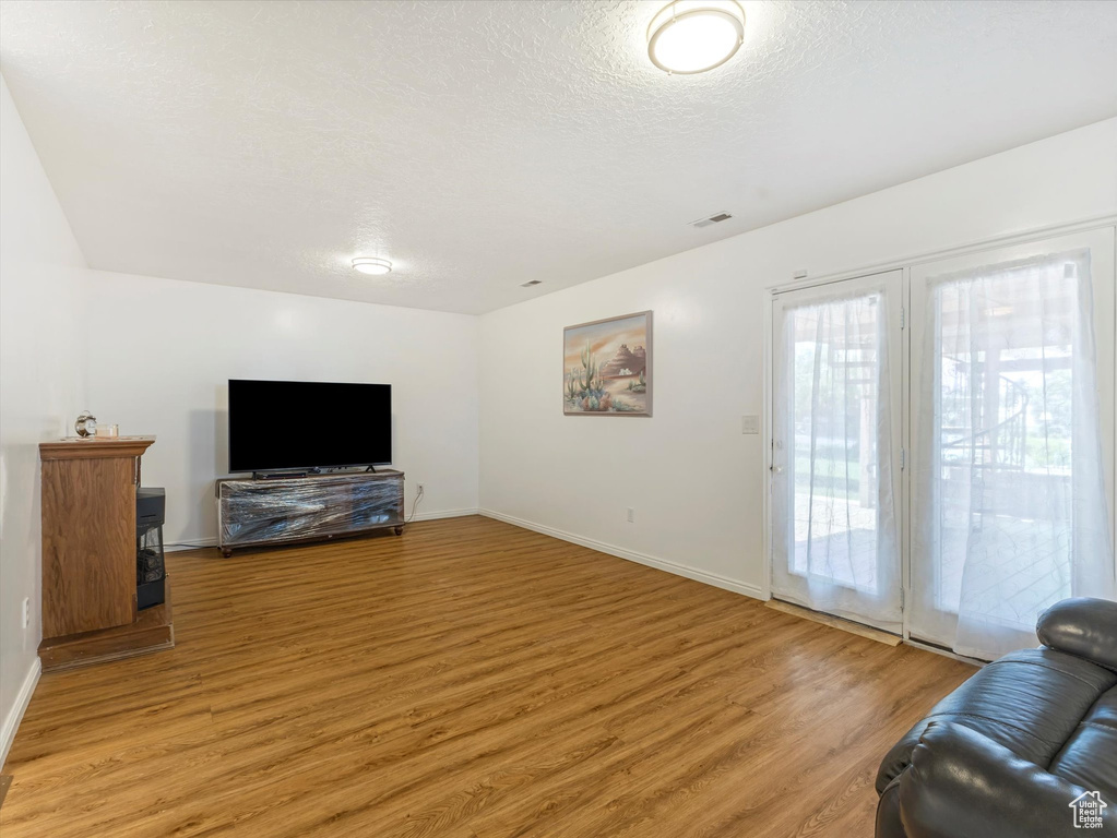 Living area featuring light wood-type flooring, baseboards, and a textured ceiling