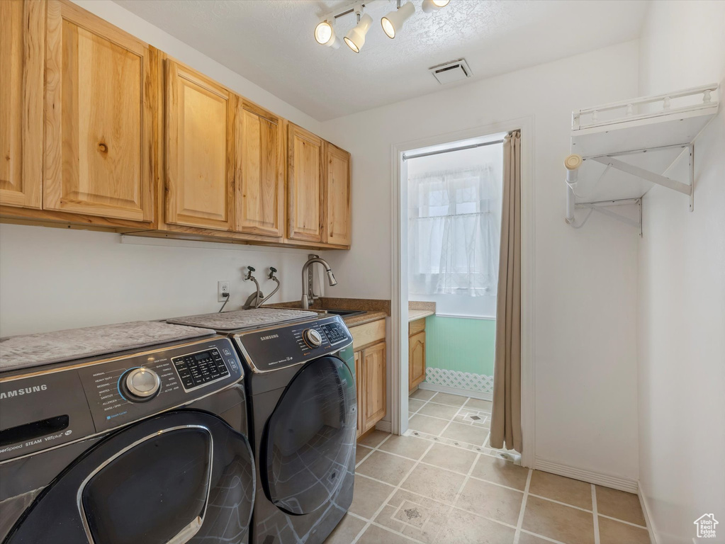 Laundry area with cabinet space, washing machine and clothes dryer, and light tile patterned floors