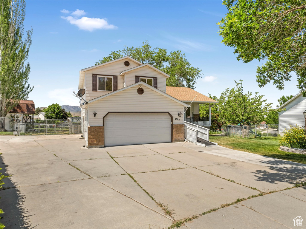 View of front of house featuring a gate, brick siding, driveway, and an attached garage