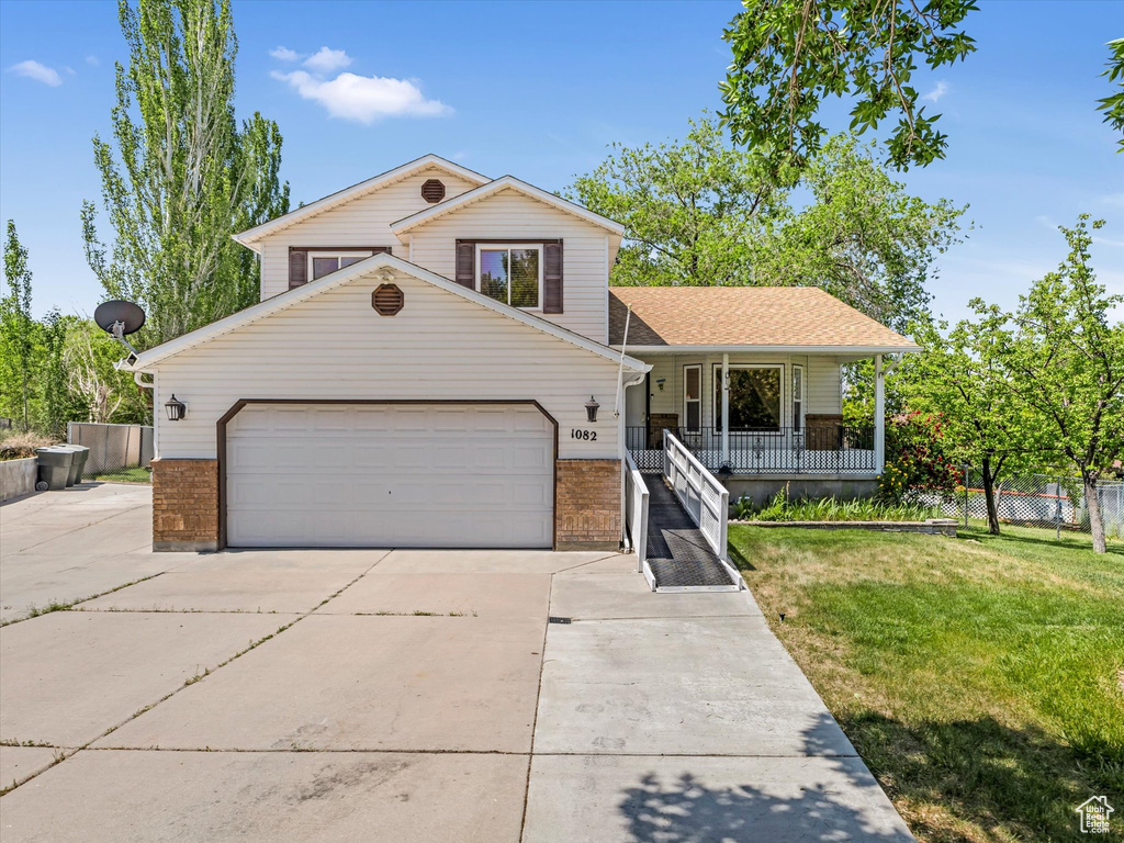 Split level home with covered porch, brick siding, concrete driveway, and a garage