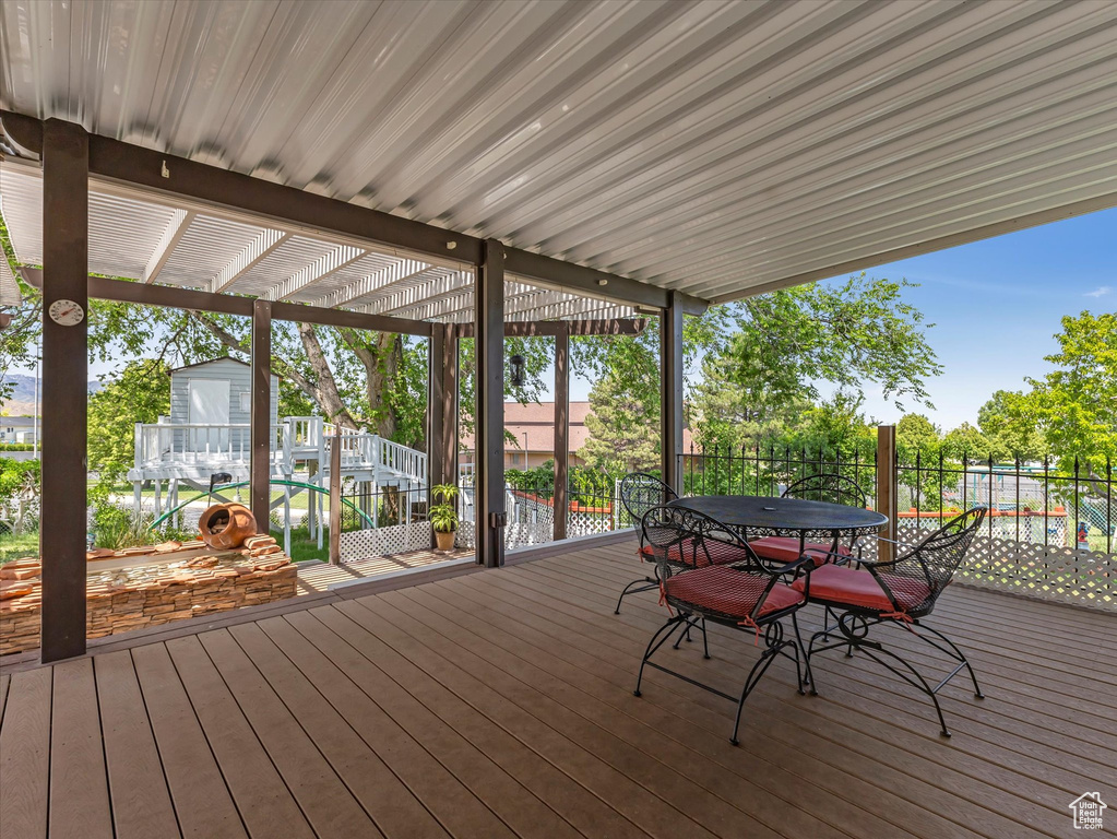 Wooden deck featuring outdoor dining area and a storage unit