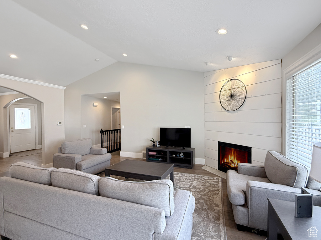 Living room featuring a fireplace, lofted ceiling, baseboards, arched walkways, and recessed lighting