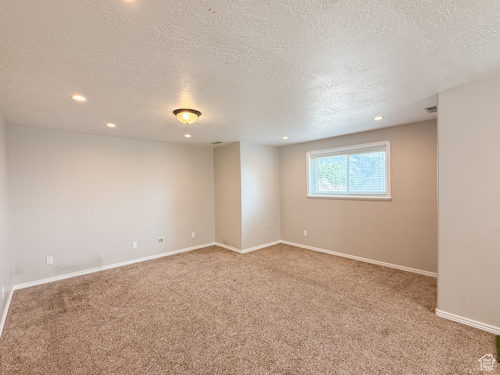 Carpeted empty room with a textured ceiling, recessed lighting, and baseboards