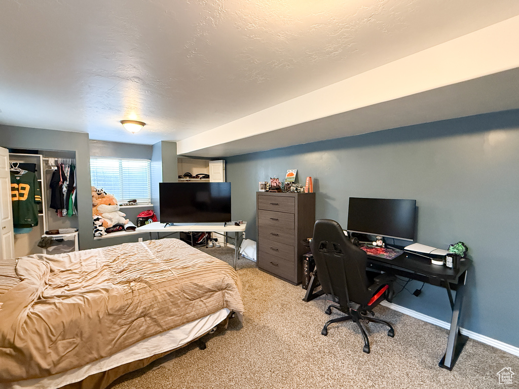Bedroom featuring light colored carpet, baseboards, a closet, and an office area