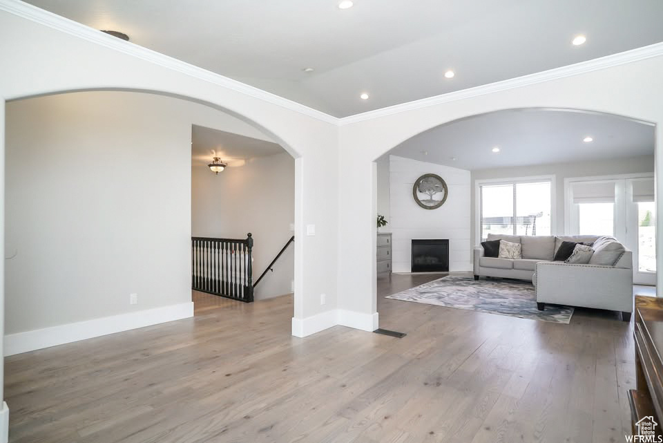 Living area with wood finished floors, arched walkways, crown molding, recessed lighting, and baseboards