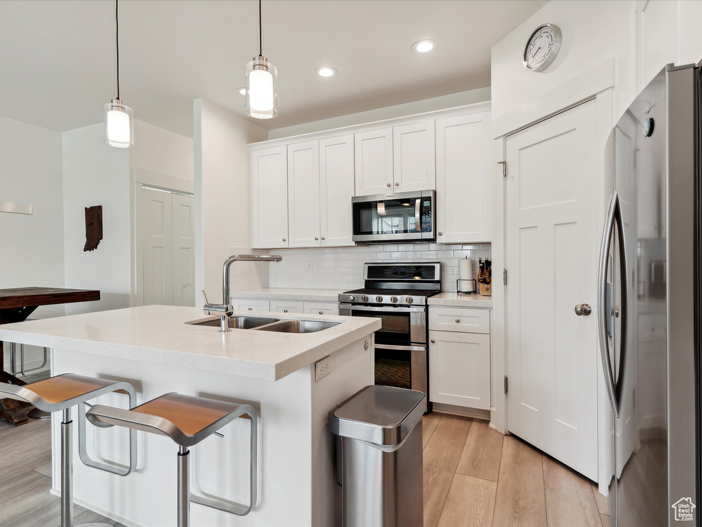 Kitchen featuring appliances with stainless steel finishes, a sink, tasteful backsplash, white cabinetry, and recessed lighting