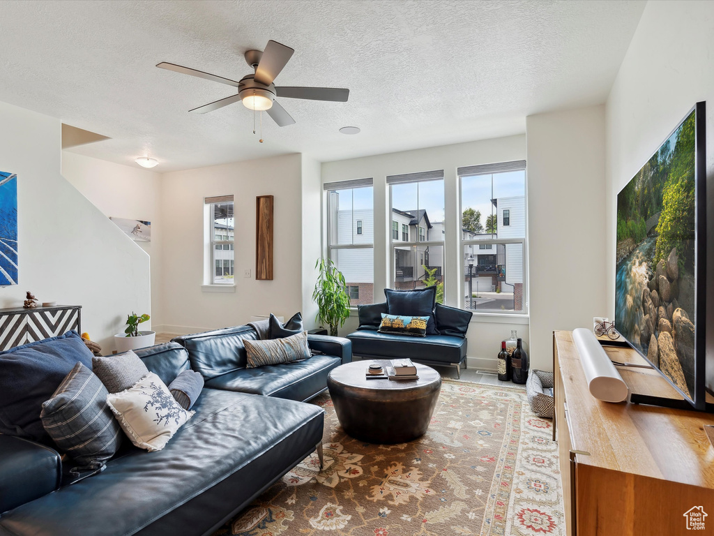 Living area featuring ceiling fan, a textured ceiling, and baseboards