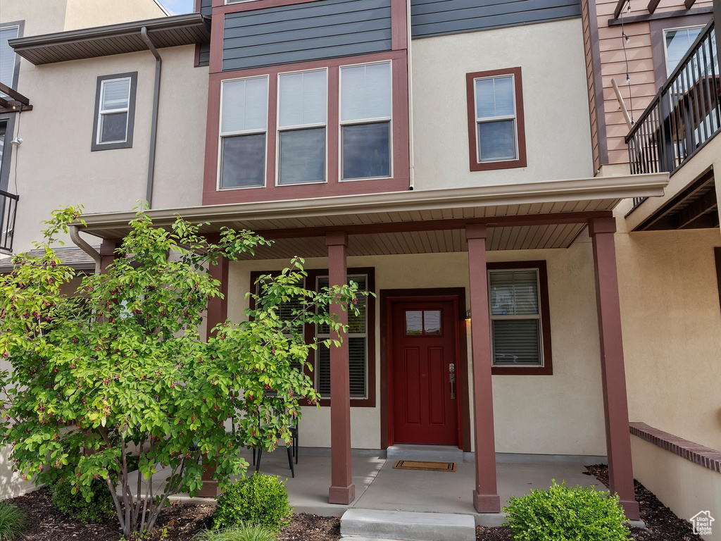 Entrance to property with covered porch and stucco siding