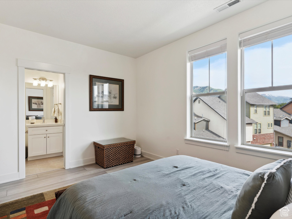 Bedroom with light wood finished floors, baseboards, and ensuite bathroom