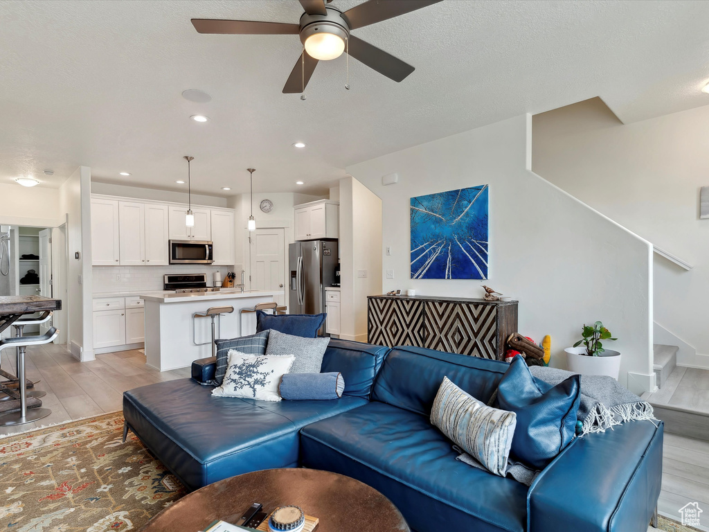 Living room featuring a ceiling fan, light wood-type flooring, stairs, and recessed lighting
