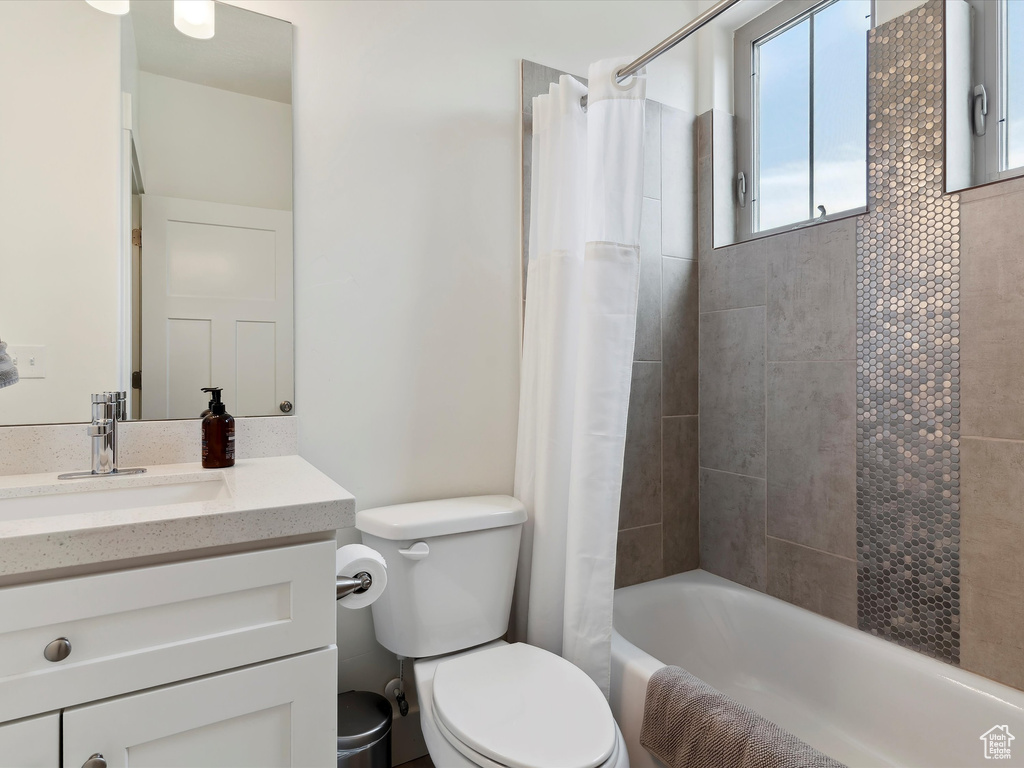 Full bath with toilet, vanity, and shower / tub combo with curtain