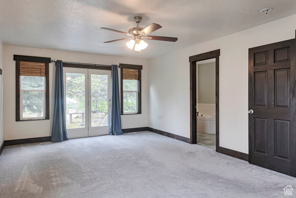 Unfurnished bedroom with light carpet, baseboards, a textured ceiling, ceiling fan, and access to outside