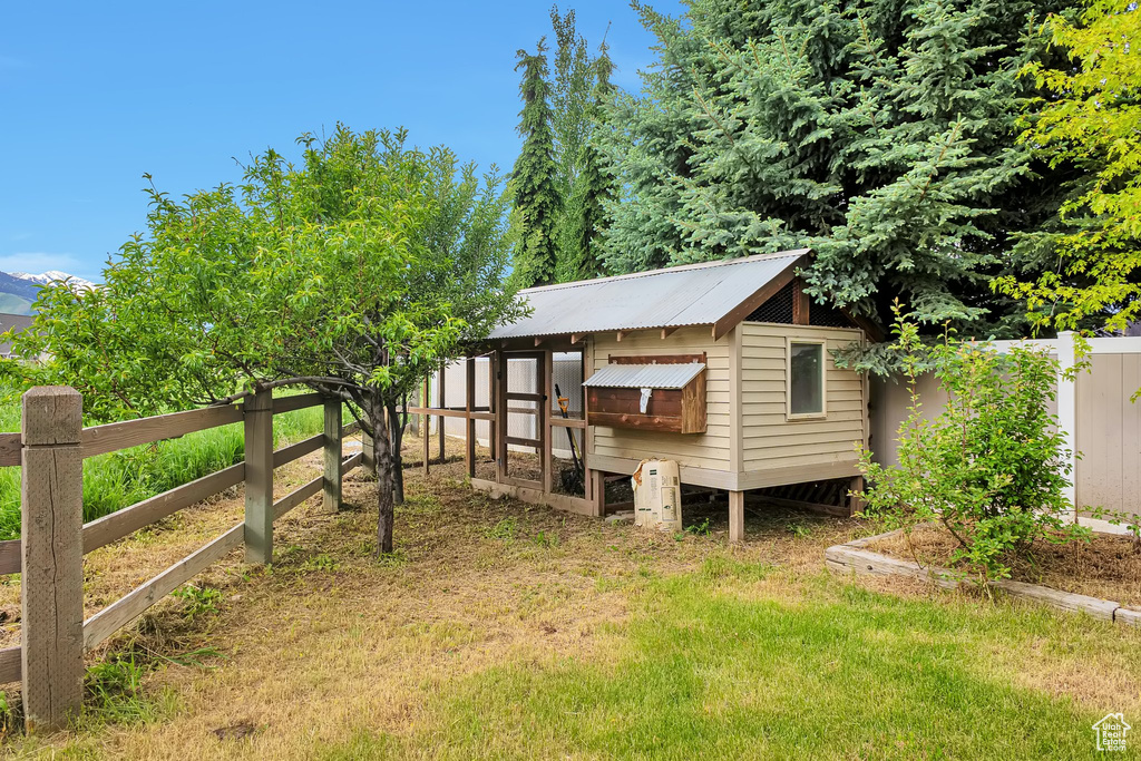 Rear view of house with exterior structure, fence, an outbuilding, and metal roof