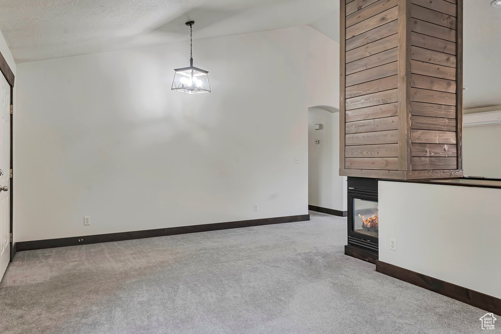 Empty room with carpet, vaulted ceiling, baseboards, and arched walkways