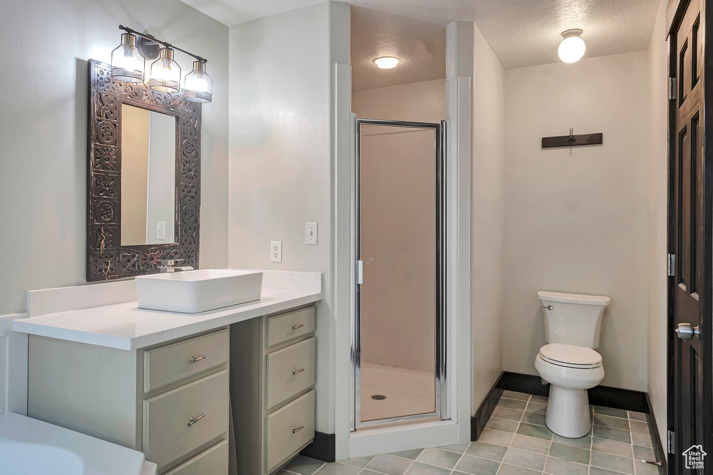 Bathroom with a shower stall, vanity, tile patterned floors, and toilet