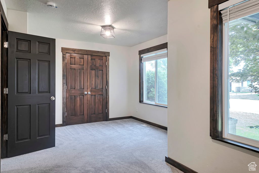 Unfurnished bedroom featuring carpet floors, baseboards, a textured ceiling, and a closet