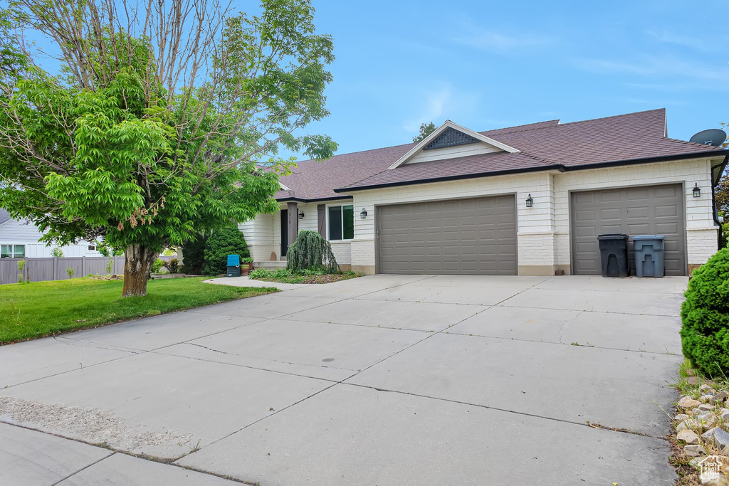 Ranch-style home featuring a garage, driveway, and roof with shingles