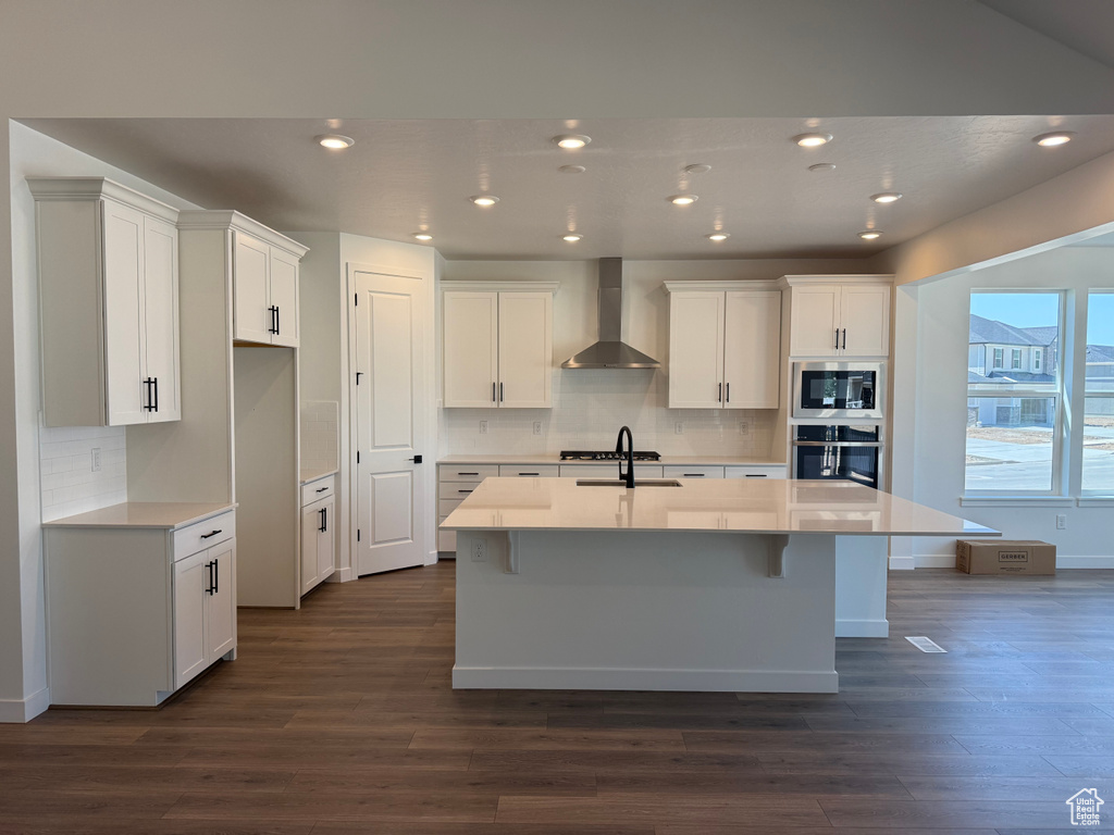 Kitchen featuring wall chimney exhaust hood, dark wood finished floors, backsplash, and recessed lighting