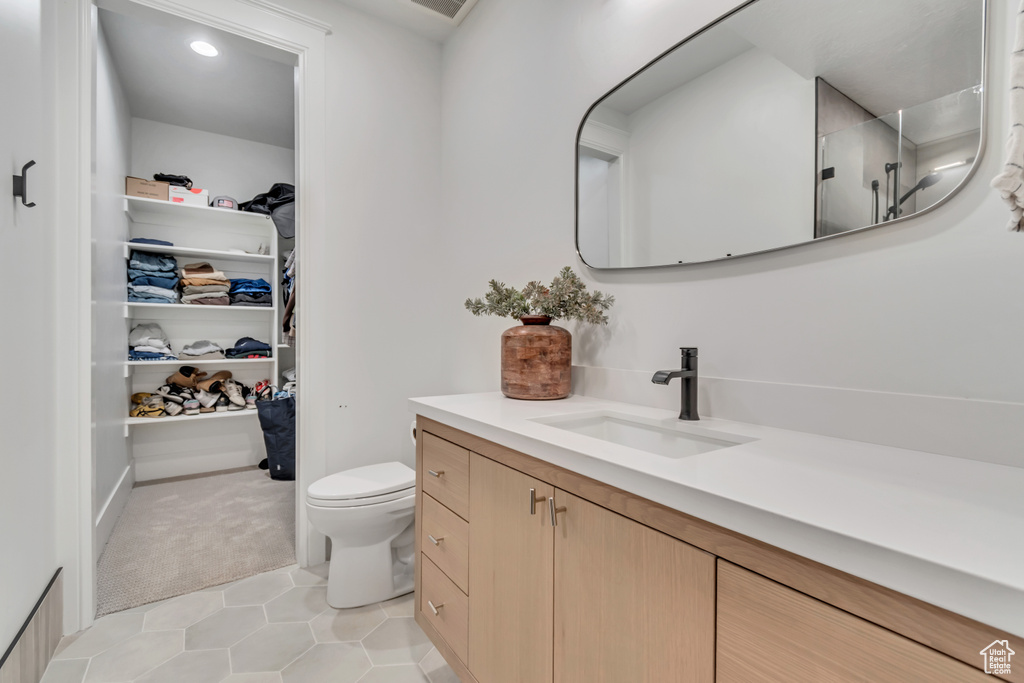 Full bathroom featuring vanity, toilet, a walk in closet, tile patterned floors, and a shower