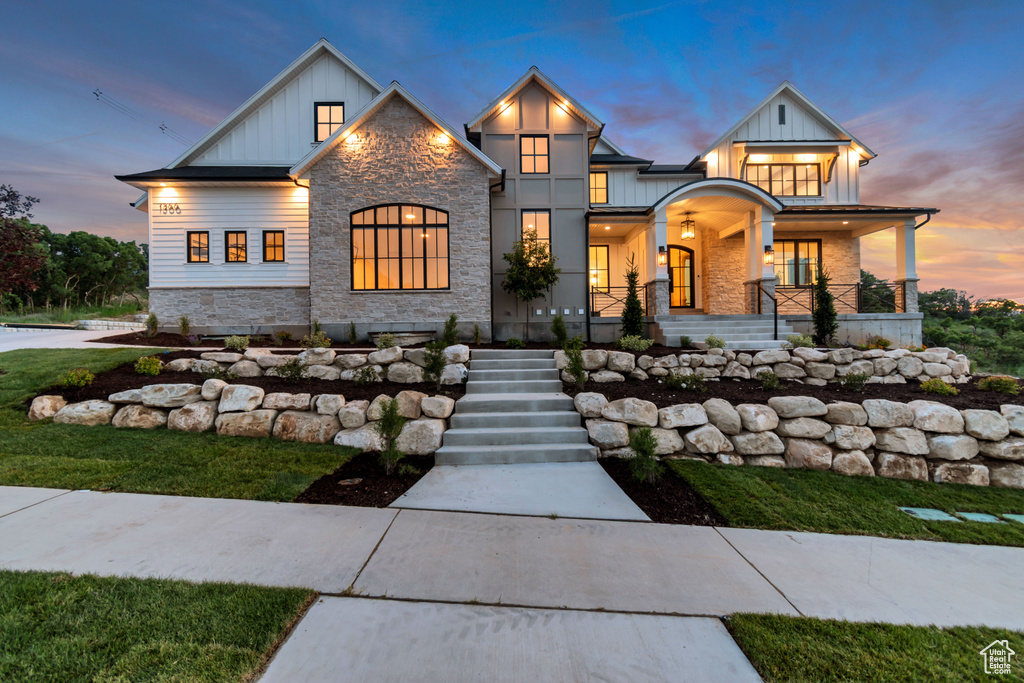 View of front of property with board and batten siding, stone siding, covered porch, and stairs