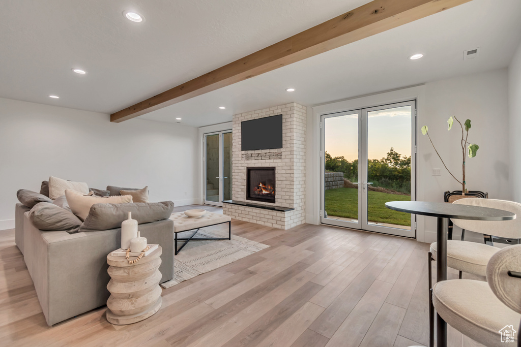 Living area featuring light wood-type flooring, beam ceiling, a brick fireplace, and recessed lighting