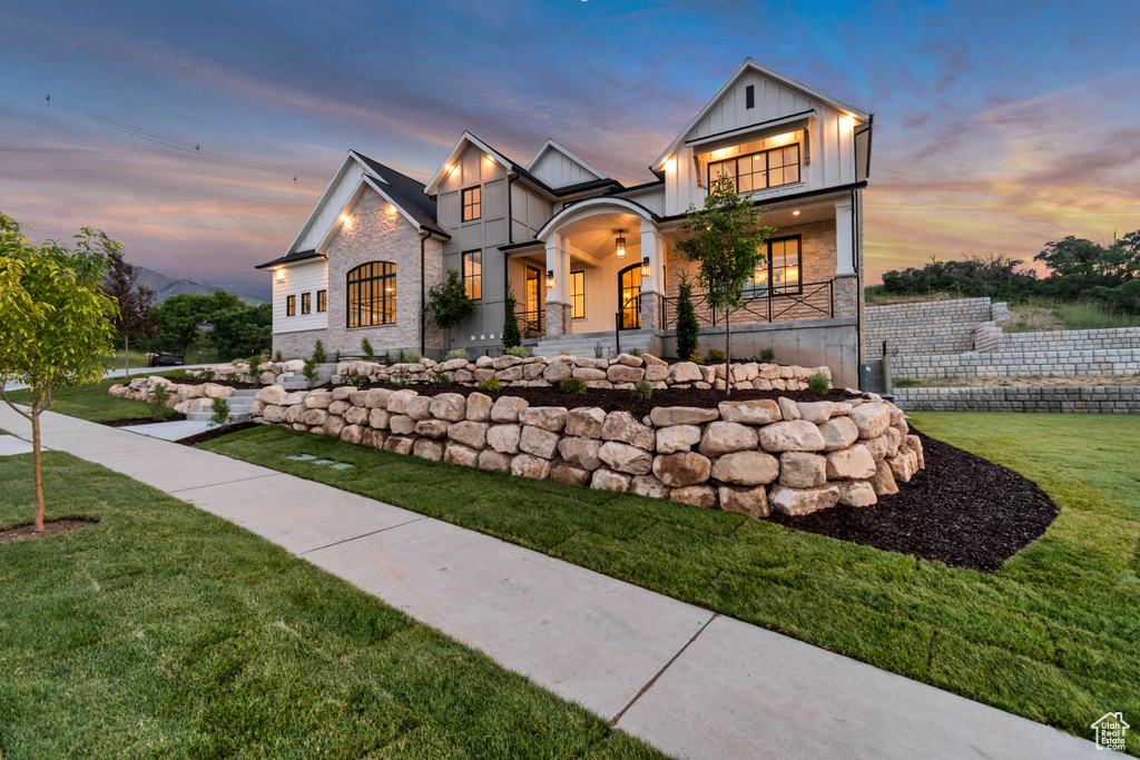 View of front of home with board and batten siding, a front lawn, and covered porch