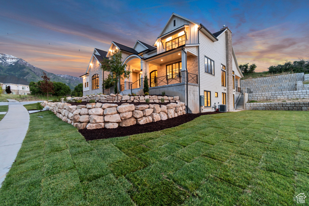View of front of house with central AC, a front yard, and board and batten siding