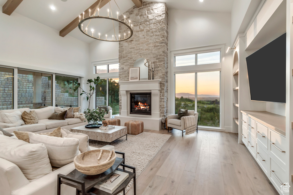 Living area featuring high vaulted ceiling, beam ceiling, a chandelier, light wood-type flooring, and plenty of natural light