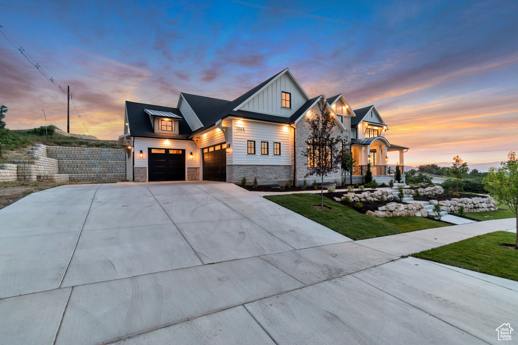 View of front of house featuring stone siding, driveway, an attached garage, and board and batten siding