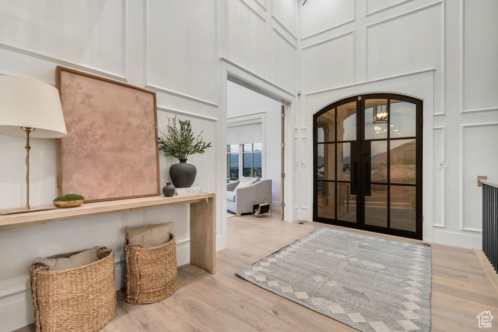 Foyer with arched walkways, wood finished floors, a decorative wall, and a towering ceiling