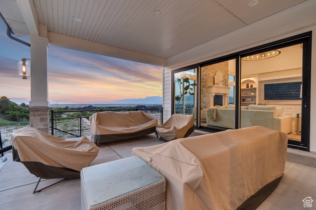 Patio terrace at dusk with a balcony, an outdoor hangout area, and a mountain view
