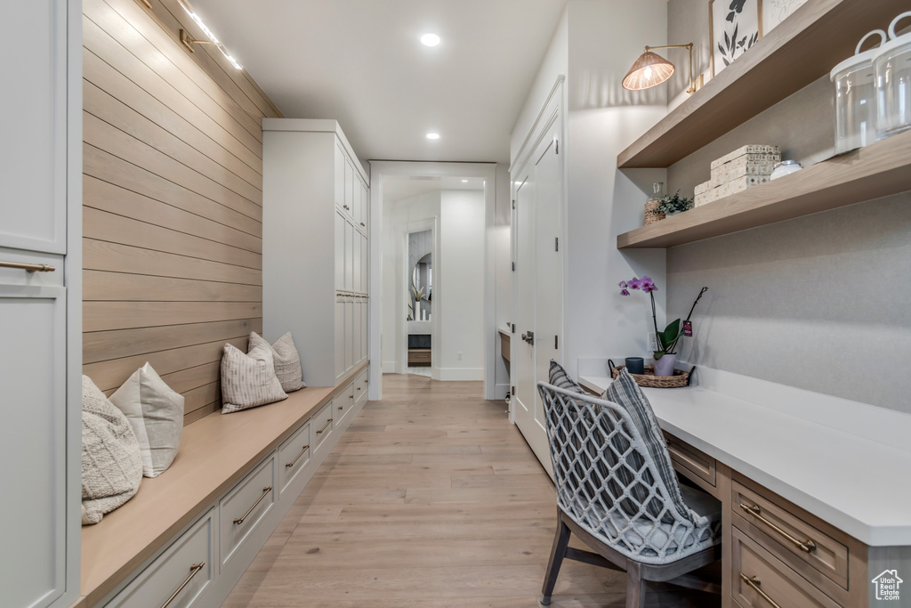Office area with built in desk, recessed lighting, light wood-style flooring, and wood walls