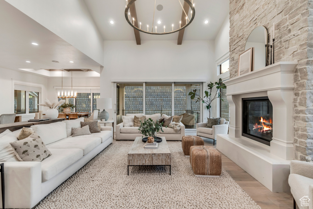 Living room featuring a chandelier, a high ceiling, a fireplace, light wood finished floors, and recessed lighting