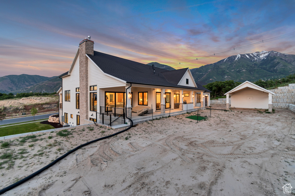 Rear view of property with a chimney, a mountain view, covered porch, and a shingled roof