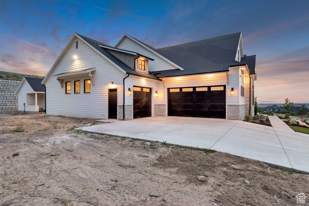Modern farmhouse style home with an attached garage, concrete driveway, stone siding, and a shingled roof