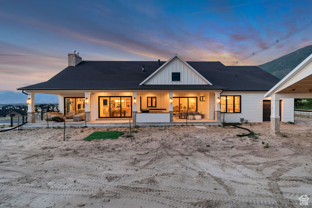 Back of property featuring board and batten siding, a chimney, and a porch