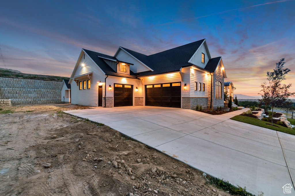 View of front of home with a garage, stone siding, driveway, and board and batten siding