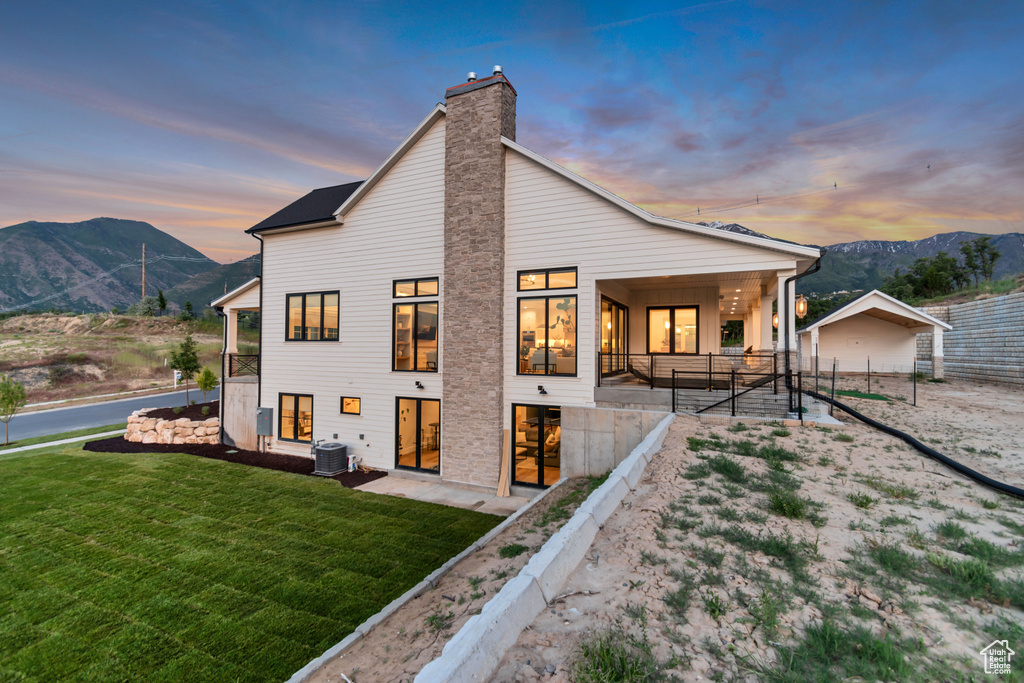 Rear view of house featuring central AC unit, a mountain view, and a chimney