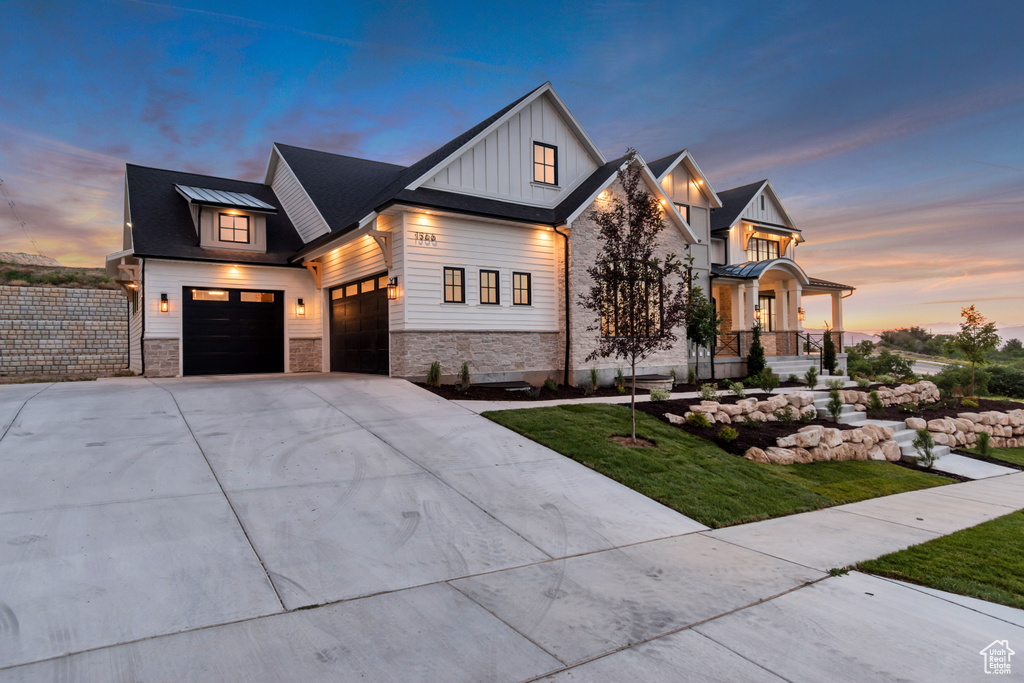 Modern farmhouse style home with board and batten siding, concrete driveway, a yard, and stone siding